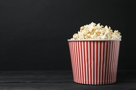 Classic red and white striped box filled with delicious, fluffy popcorn, 3D glasses on a black background.
