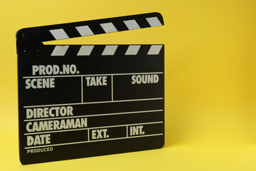 Naklejka premium Cinema clapper and reel on a yellow background 
