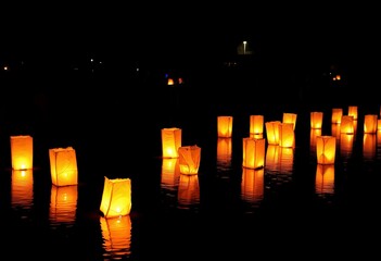 Illuminated Floating Lanterns Reflecting Warm Glow on Calm Water Surface During Peaceful Night Festival Celebration