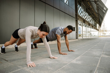 Female and male athletes standing in a push-up position on the floor
