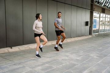 Male and female athletes laughing and running in place with high knee lifts