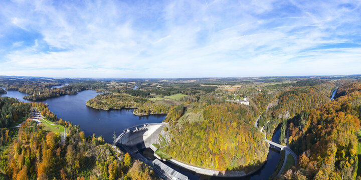 Aerial view of the Ottensteiner Stausee dam shimmering under the vast sky, nestled between lush forests painted in vibrant autumn hues, Ottenstein, Nieder&Atilde;&para;sterreich, Austria.