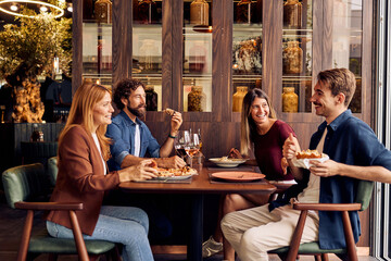 Friends Enjoying a Meal and Laughing in a Cozy Restaurant Setting