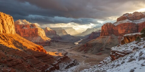Dramatic view of the Grand Canyon at sunset with snow and dramatic clouds.