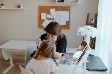 A young mother and her 3-year-old daughter play dress-up as makeup artists, sharing laughter and...