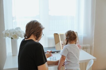A young mother and her 3-year-old daughter play dress-up as makeup artists, sharing laughter and...