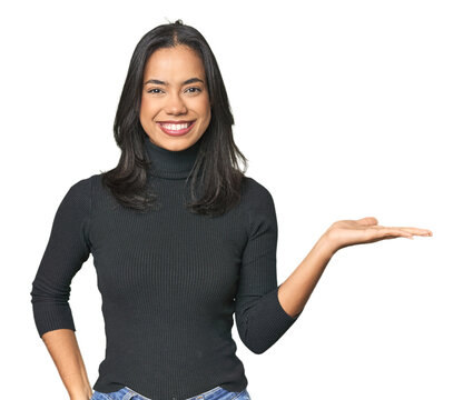 Simple portrait of a young Latina showing a copy space on a palm and holding another hand on waist.