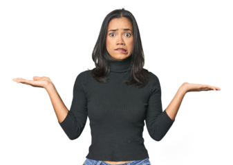 Simple portrait of a young Latina confused and doubtful shrugging shoulders to hold a copy space.