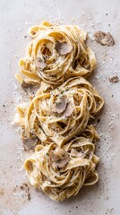 Creamy fettuccine pasta with shaved truffles and grated parmesan on neutral background