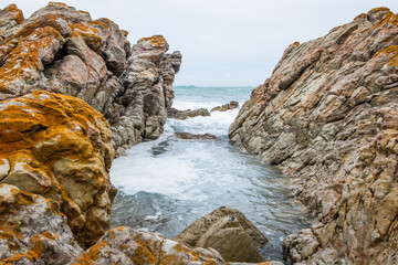 A seascape image of waves rolling in-between some ocean rocks