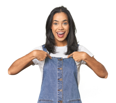Simple portrait of a young Latina surprised pointing with finger, smiling broadly.