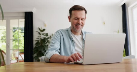 Video of smiling adult man opening and using laptop at home while sitting at table - Powered by Adobe