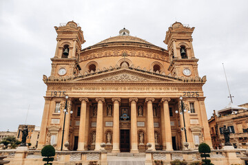 Mosta, Malta - April 14, 2025: The Mosta Rotunda, also known as the Mosta Dome, featuring a grand neoclassical facade with Corinthian columns, statues, and twin bell towers