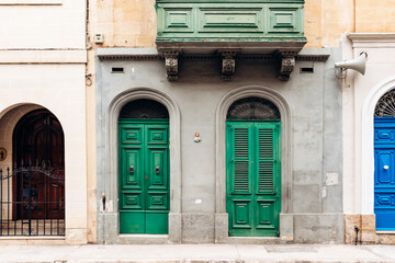 Traditional Maltese facade with two green doors and matching wooden balcony in the historic town of...