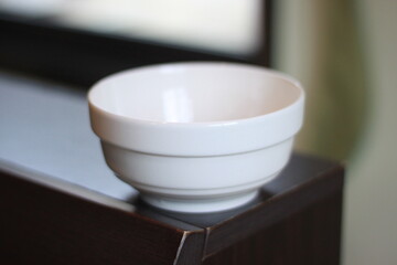A clean white ceramic bowl placed on a wooden surface with natural light coming from the window. The simple and minimal design highlights elegance, functionality, and everyday household use.