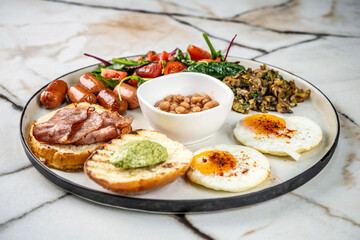 A delicious and hearty full breakfast plate with eggs, bacon, and sausages.