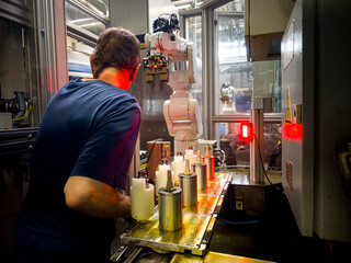 Worker operating robotic machine in a manufacturing facility during daytime