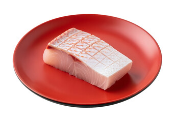 A rectangular piece of raw fish, attractively arranged on a vibrant red plate, highlights its delicate texture and vibrant hues against a striking black background.