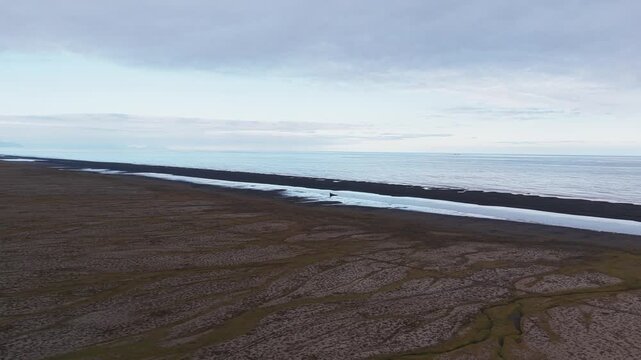 Aerial view of the stark contrast between the dark volcanic sands and the pale blue waters meeting at the black beach, Clyne Castle, Sveitarf&eacute;lagi&eth; Hornafj&ouml;r&eth;ur, Iceland.