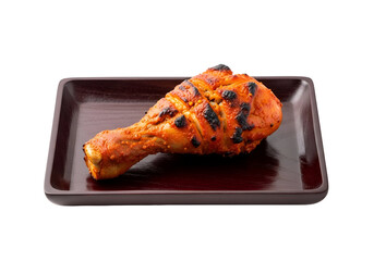 A delicious, single, grilled chicken drumstick, vibrant with fiery, reddish-orange spices and dark char marks, sits elegantly on a dark wooden platter, highlighted against a stark black backdrop.