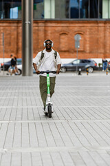 Obraz premium A male worker rides a scooter and listens in headphones