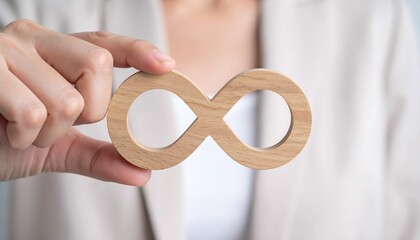 Female hand pressing wooden infinity sign symbolizing business growth