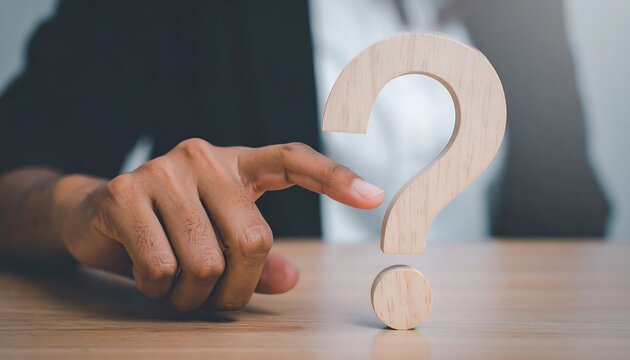 Wooden question mark icon touched by businesswoman hand symbol of curiosity and guidance