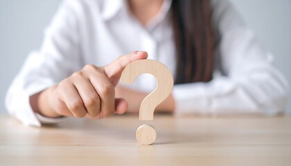 Businesswoman hand touching wooden question mark icon symbolizing decision making