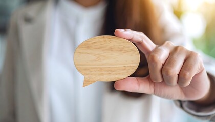 Female professional hand touching wooden speech bubble icon for business communication
