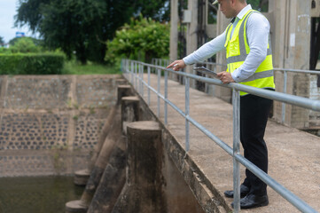 A male dam engineer is checking the water volume in the reservoir and recording it in a document