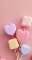 Obraz premium Pastel-colored marshmallows on sticks against a pink background