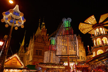 Christmas fair at night with illuminated gifts and festive carousel in historic city center. Festive Christmas market in Wroclaw, Poland. Concept of holiday celebration, winter tradition and tourism