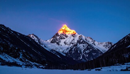 Snow-capped mountain peak illuminated by golden sunlight against a dark blue sky, flanked by shadowy slopes and snowy foreground