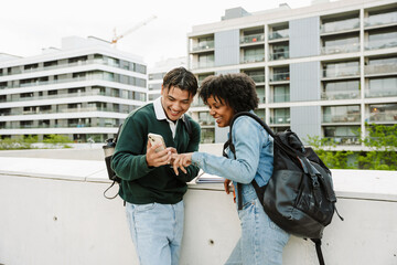 Male and female students laughing and looking at the phone he is holding