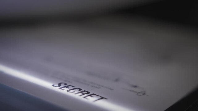 Government report labeled secret is passing through copy machine fax or scanner. Dark room desk military secrets stolen and exposed revealed to public. Conspiracy and fraud stolen by spy agency