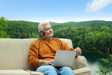 Senior man listening to sounds of nature which making him feel calm. Beautiful landscape on background