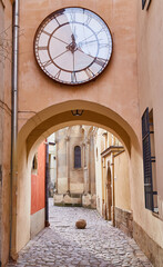 Historic cobblestone alley with a large clock in the Old Town of Lviv, Ukraine.