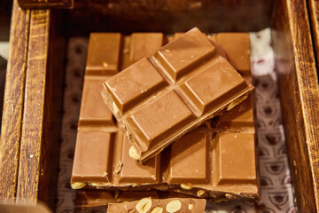 Artisanal milk chocolate bar with whole nuts in a wooden box.