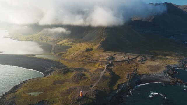 Aerial view of the Hvalnes Lighthouse on a rocky coast, where the orange tower stands out against the landscape and the ocean, Hvalnes, Sveitarf&eacute;lagi&eth; Hornafj&ouml;r&eth;ur, Iceland.