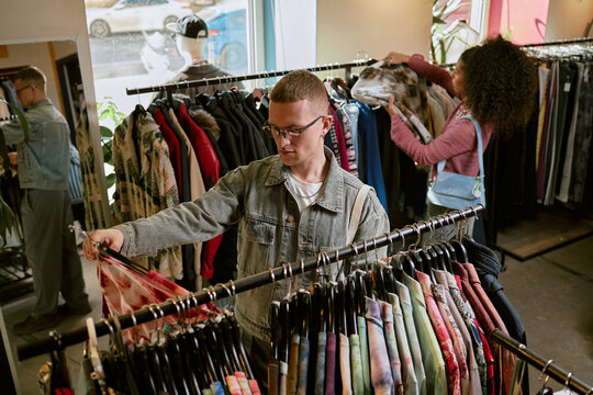 Customer choosing vintage clothing on racks in a fashion store