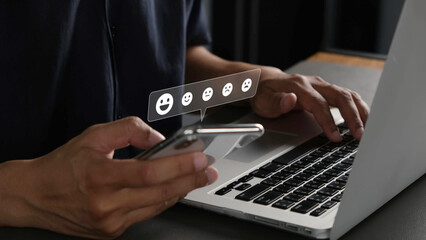 Person using smartphone and laptop for online shopping, showing satisfaction with digital service through positive feedback icons