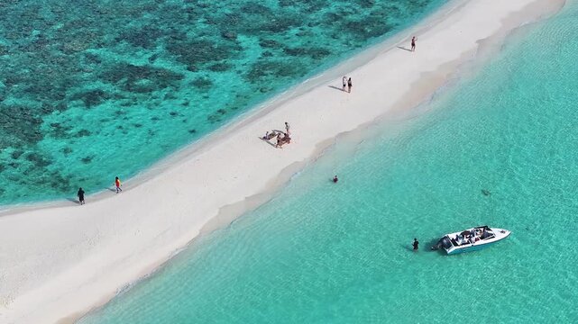 Aerial view of pristine white sandbank meeting turquoise water with people, coral reef and a boat, a tropical paradise, Thoddoo, Alif Alif Atoll, Maldives.