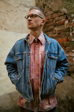 Urban man in denim jacket and streetwear style against brick wall