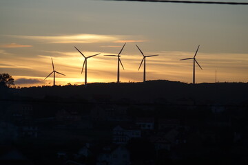 Obraz premium Tramonto mozzafiato su un campo eolico, simbolo di energia pulita e futuro sostenibile. Silhouette di turbine a vento contro cieli infuocati