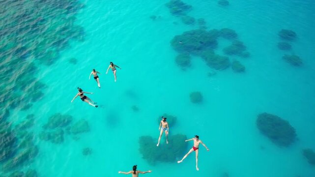 Aerial view of snorkelers swimming above coral reef in crystal-clear water near the Gili Islands, Indonesia. Tropical paradise and marine adventure in turquoise sea.