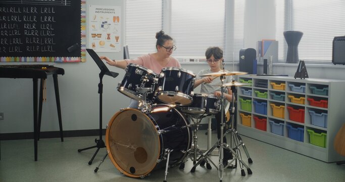 Talented Boy Playing Drums During Percussion Class in Elementary School, Practicing Sense of Rhythm. Teacher Teaching Young Musician to Play Drum Kit on Music Lesson for Learning Musical Instruments.