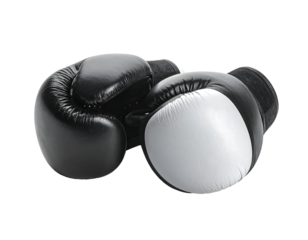 A pair of black and white leather boxing gloves lie on a black background, one glove mostly visible, the other partially obscured