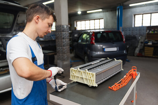 Serviceman working on electric vehicle battery pack in car workshop