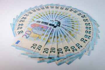 Circular arrangement of 20 euro banknotes spread out like a fan on a white background, symbolizing...