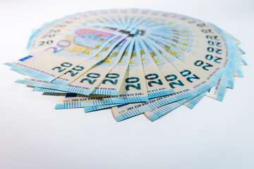 Fototapeta premium Circular arrangement of 20 euro banknotes spread out like a fan on a white background, symbolizing finance, savings, and monetary wealth.